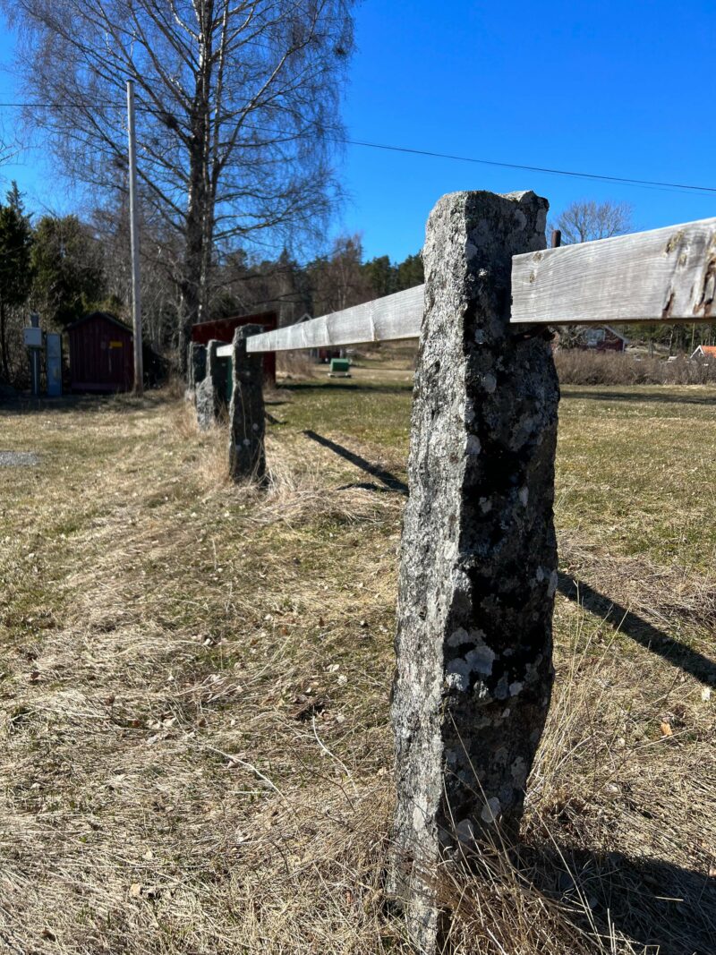 Stone fence post with wooden rail in a rural field on Arholma Island, Stockholm Archipelago Trail
